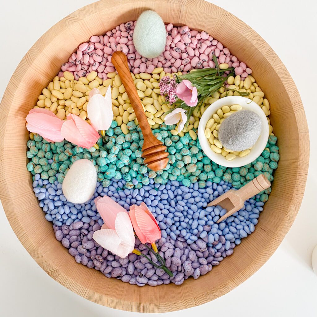 Sensory bin using various beans dyed in pastel colours using paint. This is a great spring or easter sensory bin.