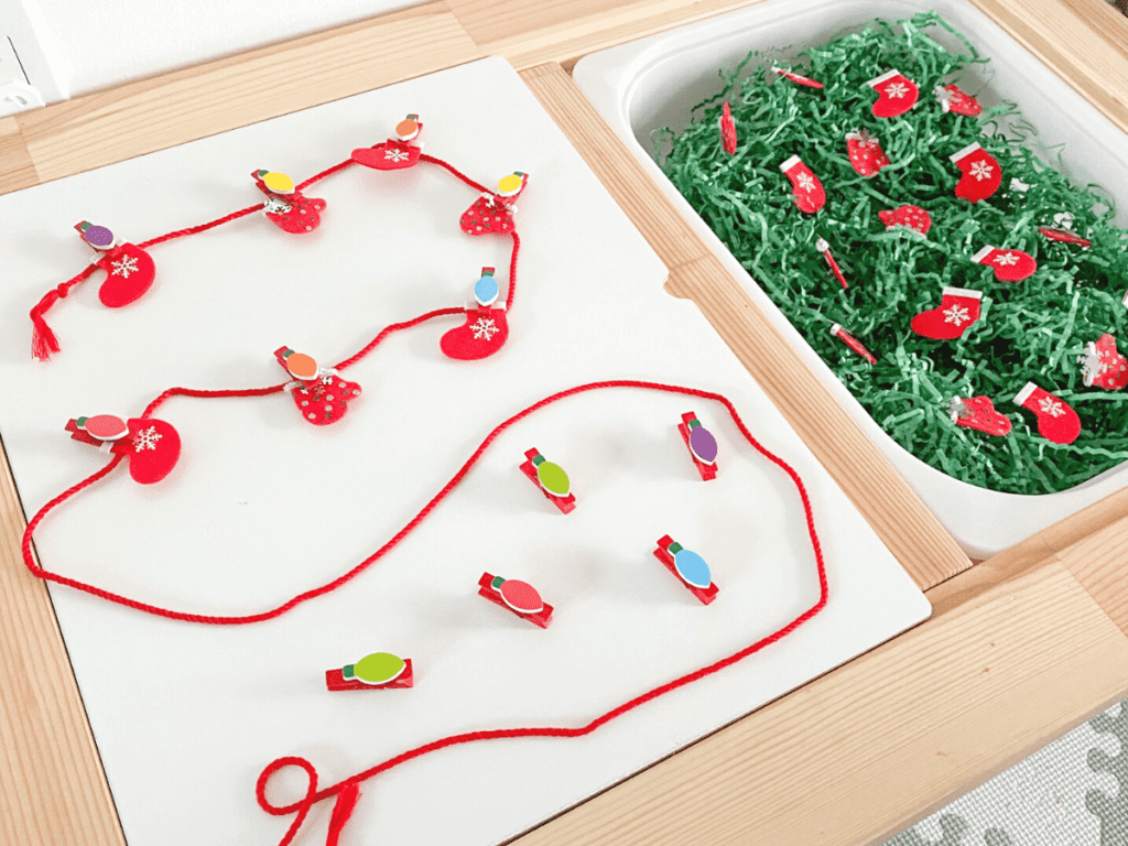 This Christmas-themed sensory bin is a perfect fine motor activity for toddlers! Have them hang the mittens on the string using the clothespins.