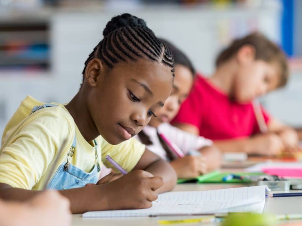 kids writing in a notebook in a classroom