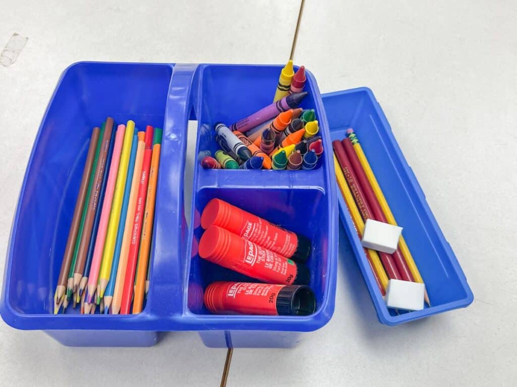 Caddie filled with school supplies, pencil crayons, glue sticks, crayons, pencils, and erasers